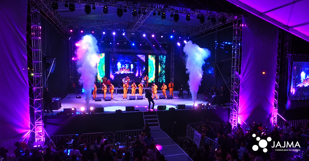 Escenario con músicos, pantallas LED, iluminación y efectos de humo durante el evento de Jajma.