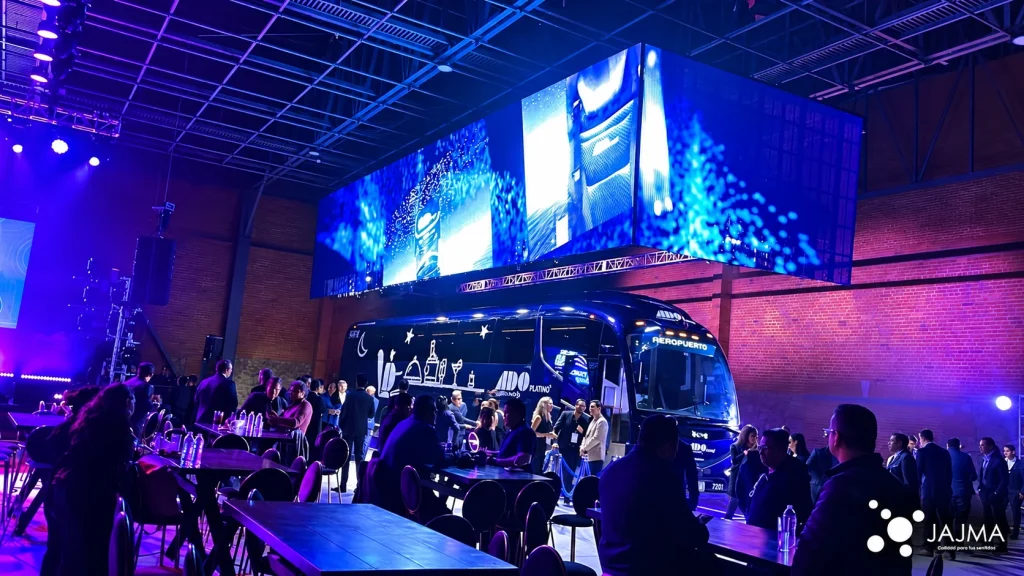 El autobús ADO Platino durante la presentación, rodeado de asistentes y pantallas LED.