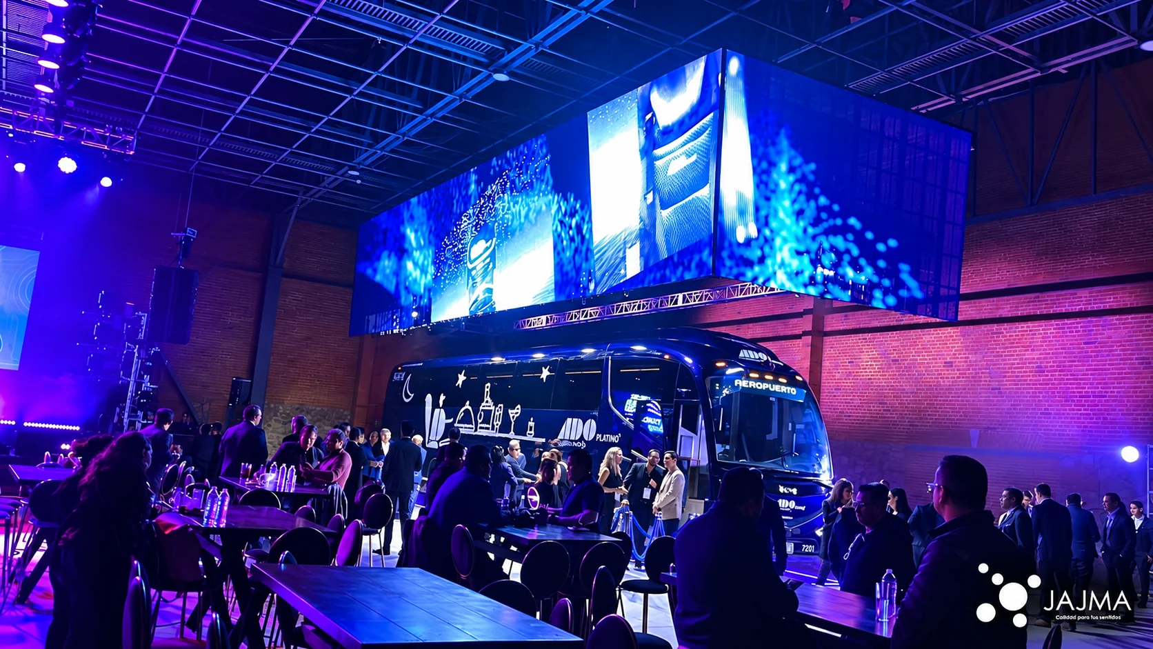 El autobús ADO Platino durante la presentación, rodeado de asistentes y pantallas LED.