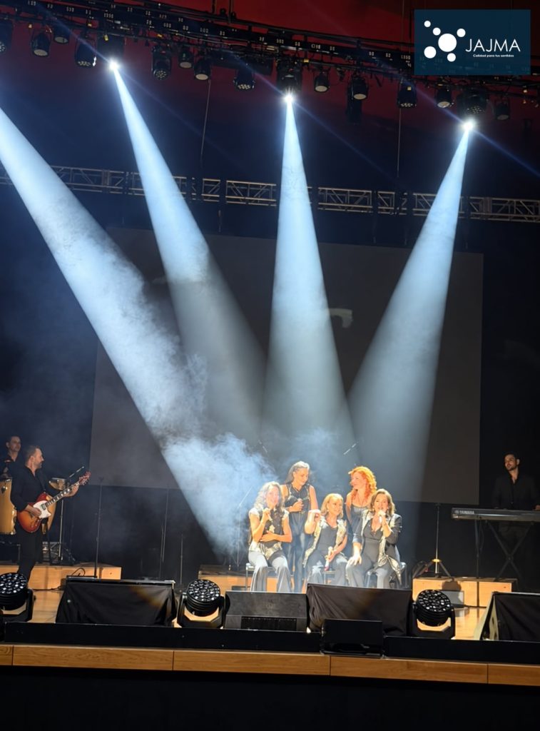 Intérpretes bajo haces de luz blanca durante Noche Romántica en El Cantoral.